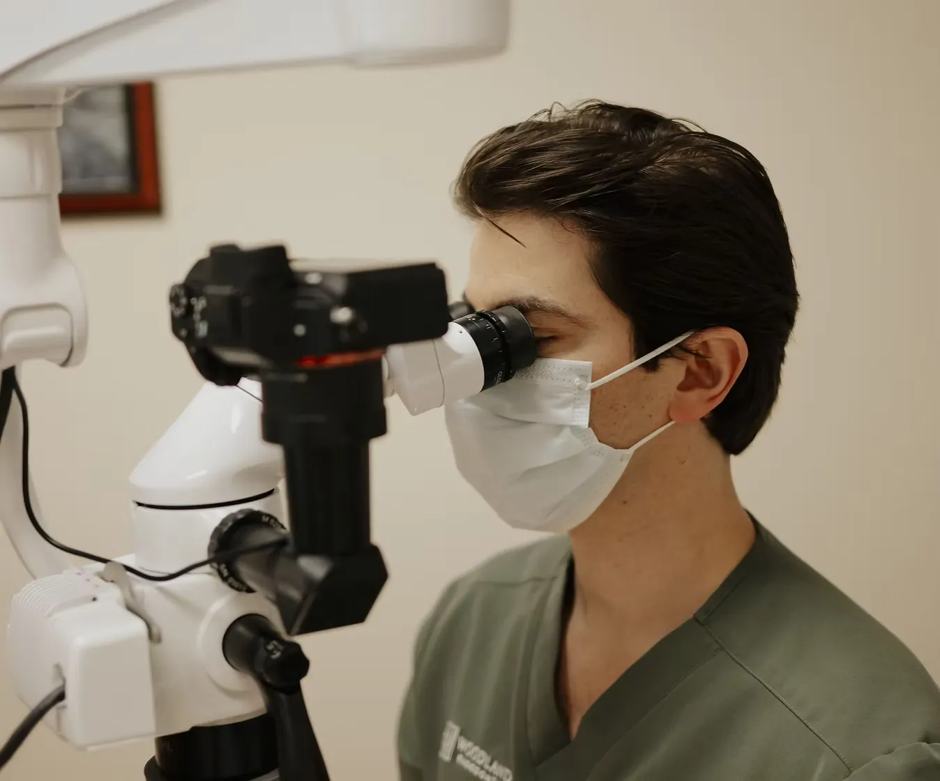 Endodontist examining a tooth under a surgical microscope at Woodlands Endodontics